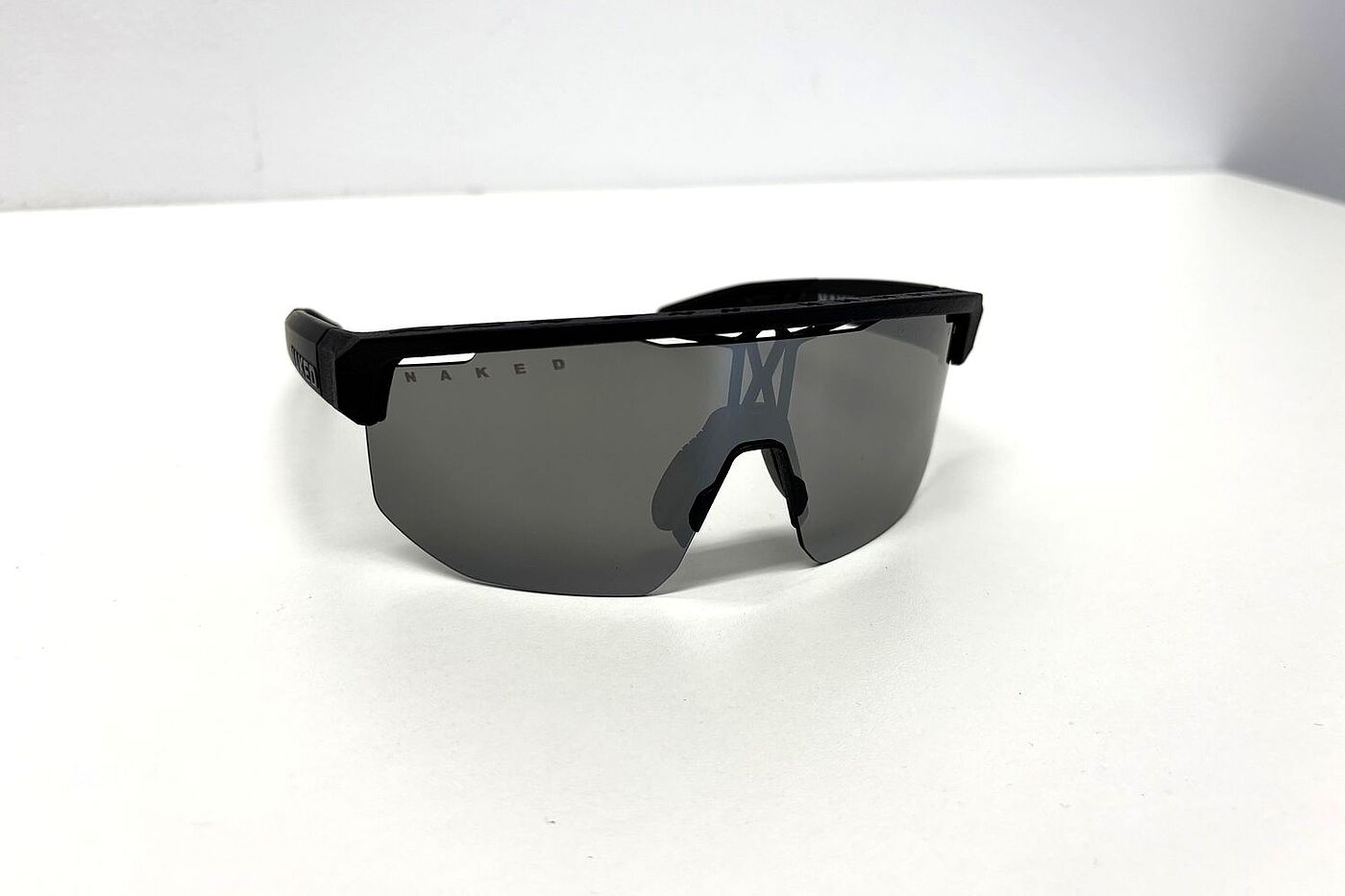 Eine Radbrille mit getönter Scheibe liegt auf einem weißen Tisch. 